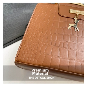 Detailed shot of brown crocodile embossed leather handbag with golden deer charm pendant