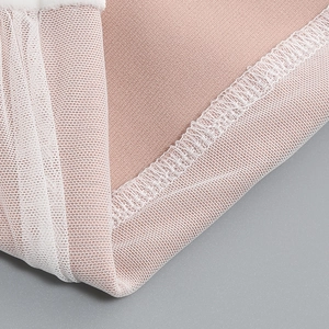 Detailed close-up of pink velvet fabric with mesh stitching and reinforced seams