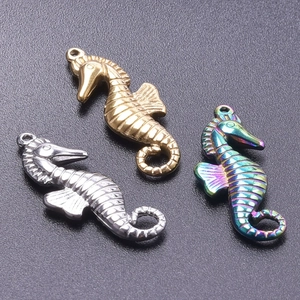 Macro shot of seahorse pendants in gold silver and rainbow finishes on textured background