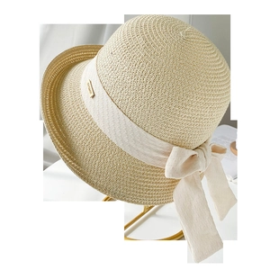 Détail d'un chapeau de paille avec ruban beige et logo doré sur support métallique