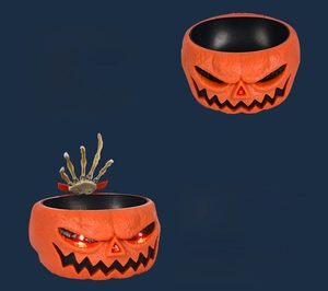 Macro view of Halloween electric pumpkin candy bowl with glowing eyes and moving skull hand