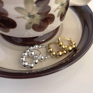 Close-up of gold and silver S925 sterling silver beaded hoop earrings on ceramic plate