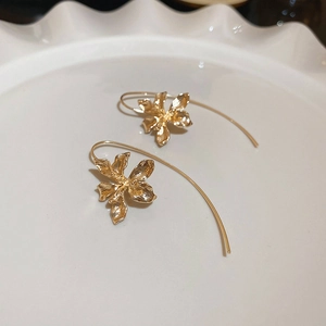 Detail of vintage gold iris flower earrings with textured petals on a ceramic dish