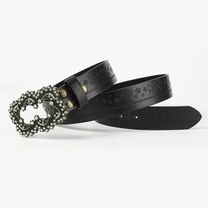 Detail of black punk belt featuring embossed stars and a sparkling rhinestone heart buckle