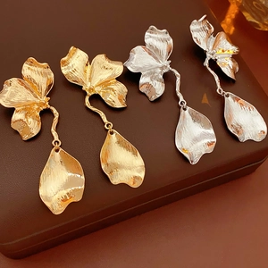 Detailed view of floral metal earrings in gold and silver finishes with textured petals