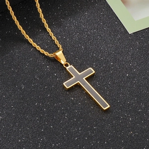 Detailed macro view of a gold cross pendant with black enamel center on a gold twist chain