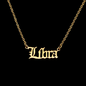 Close-up of golden Libra zodiac pendant in Gothic font with polished curb chain detail