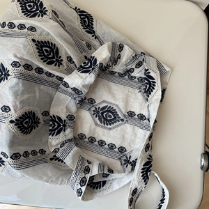 Close-up of ethnic blue embroidery on a white linen shoulder bag with geometric patterns