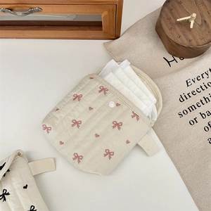 Dettaglio della pochette trapuntata con ricamo a fiocco rosa e chiusura con bottone a pressione