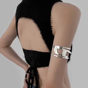Close-up of a silver hollow geometric arm cuff worn over a black faux fur halter top