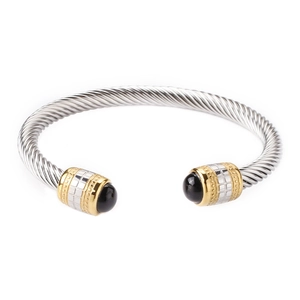 Macro detail of silver cable twist bangle with gold accents and black onyx stone tips