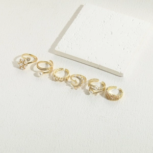 Detailed view of a 6-piece gold-plated ring set with pearls and rhinestones on white stone