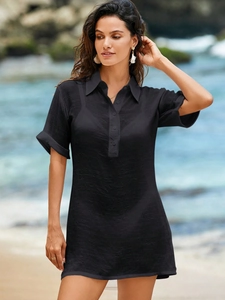 Detail of black short sleeve textured cotton dress with button placket in beach setting