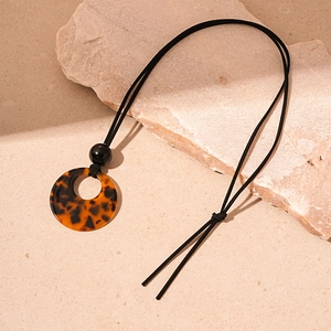 Detail shot of a retro geometric tortoise shell resin pendant on a black cord necklace