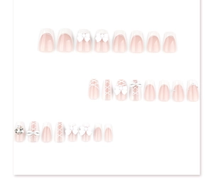 Detail of French style press-on nails with 3D white bows and crystal heart accents