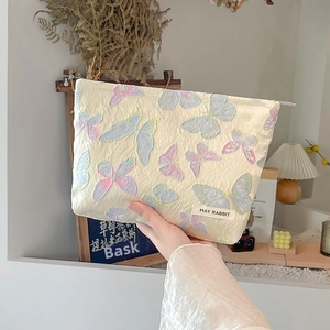 Detail of floral jacquard makeup bag with butterfly embroidery and May Rabbit logo tag