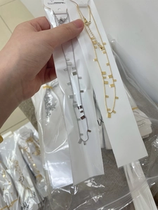 Detail showing gold and silver stainless steel sequin necklaces in transparent packaging