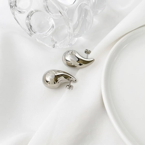 Polished silver bean stud earrings with flower engraving on a white minimalist background