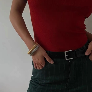 Close-up of gold and silver Tubogas flexible metal bracelets worn by a fashion model