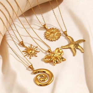 Set of five gold necklaces with starfish sun and bow pendants on cream silk fabric