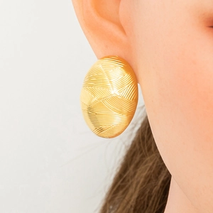 Close-up of golden oval stud earring with knitted texture on model for women