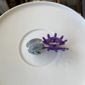 Detail of sparkly silver and purple acetate hair clips with glitter finish and gold springs