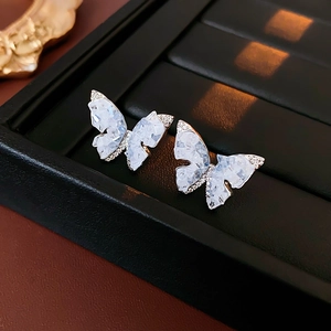 Gros plan de boucles d'oreilles papillon en cristal et zircons sur plateau noir