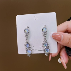Macro view of long S925 silver needle earrings with liquid metal and moonstone texture