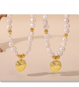 Detailed view of baroque pearl earrings with textured 18k gold PVD plated pendants