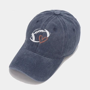 Close-up of navy blue washed denim baseball cap with rugby ball and red heart embroidery