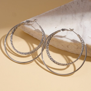 Detail of silver double layered hoop earrings with textured inner ring on a stone