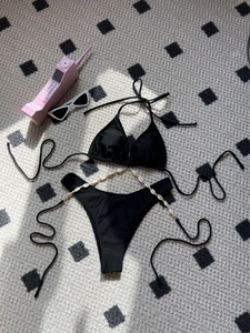 Sexy black halter bikini set with shell chain details on bohemian flat lay display