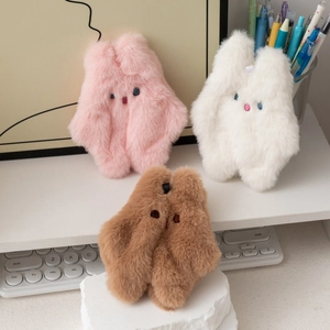 Porte-monnaie lapins en peluche rose, blanc et marron sur un bureau minimaliste