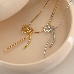 Detailed macro of a bow-knot pendant necklace with zircon accents in a ceramic dish