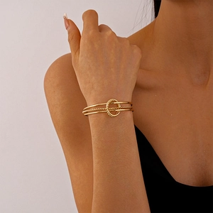 Detail of a gold-layered geometric cuff bracelet featuring twisted and smooth ring textures