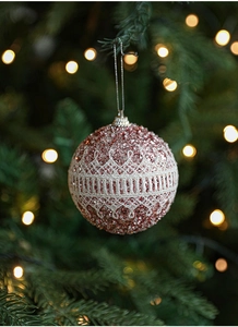 Close-up of pink Christmas bauble with white lace trim hanging on a festive tree