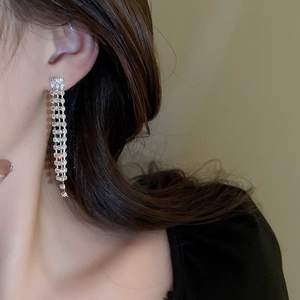 Close-up of elegant long silver tassel earrings with sparkling rhinestones on model