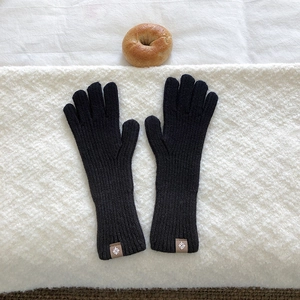 Close-up of black knitted gloves with ribbed texture and minimalist logo tag detail