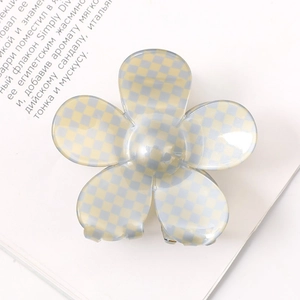 Detail of flower shaped hair claw clip with blue and yellow checkered pattern on white book