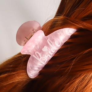 Pink marble acetate hair claw clip with white Bride text and heart on brown hair