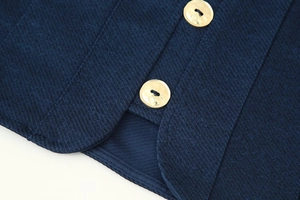 Détail du tissu en sergé bleu marine et des boutons métalliques dorés sur un gilet de costume