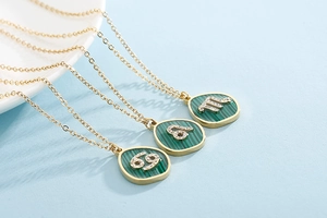 Detailed close-up of golden necklace with green malachite pendant and crystal constellations