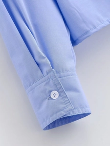 Close-up of light blue shirt cuff featuring white button and professional stitching detail