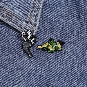 Detail of vintage pin-up girl and retro sea monster enamel pins on denim jacket fabric