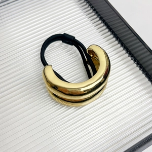 Detailed view of glossy gold metallic arched ponytail cuff with black elastic hair tie
