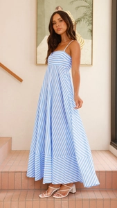 Detail of a flowy blue and white striped maxi dress with thin straps and a wide hemline