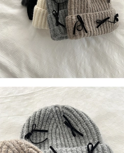 Detail shot of the coarse knit texture and black velvet bow on the cozy beanie hat