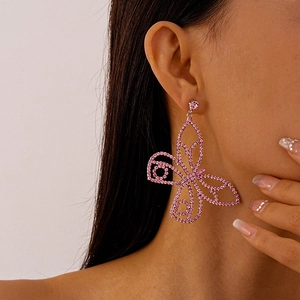 Close-up of pink crystal butterfly earring worn by a model showing luxury dangle style