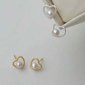 Close-up of heart-shaped twisted metal earrings with white freshwater pearls in jewelry box