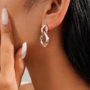 Detail of silver twisted double-loop earrings with cubic zirconia on model